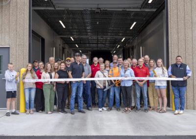 Community members and Woody's Trucking staff holding the ribbon before the cutting ceremony at the new wash-bay expansion
